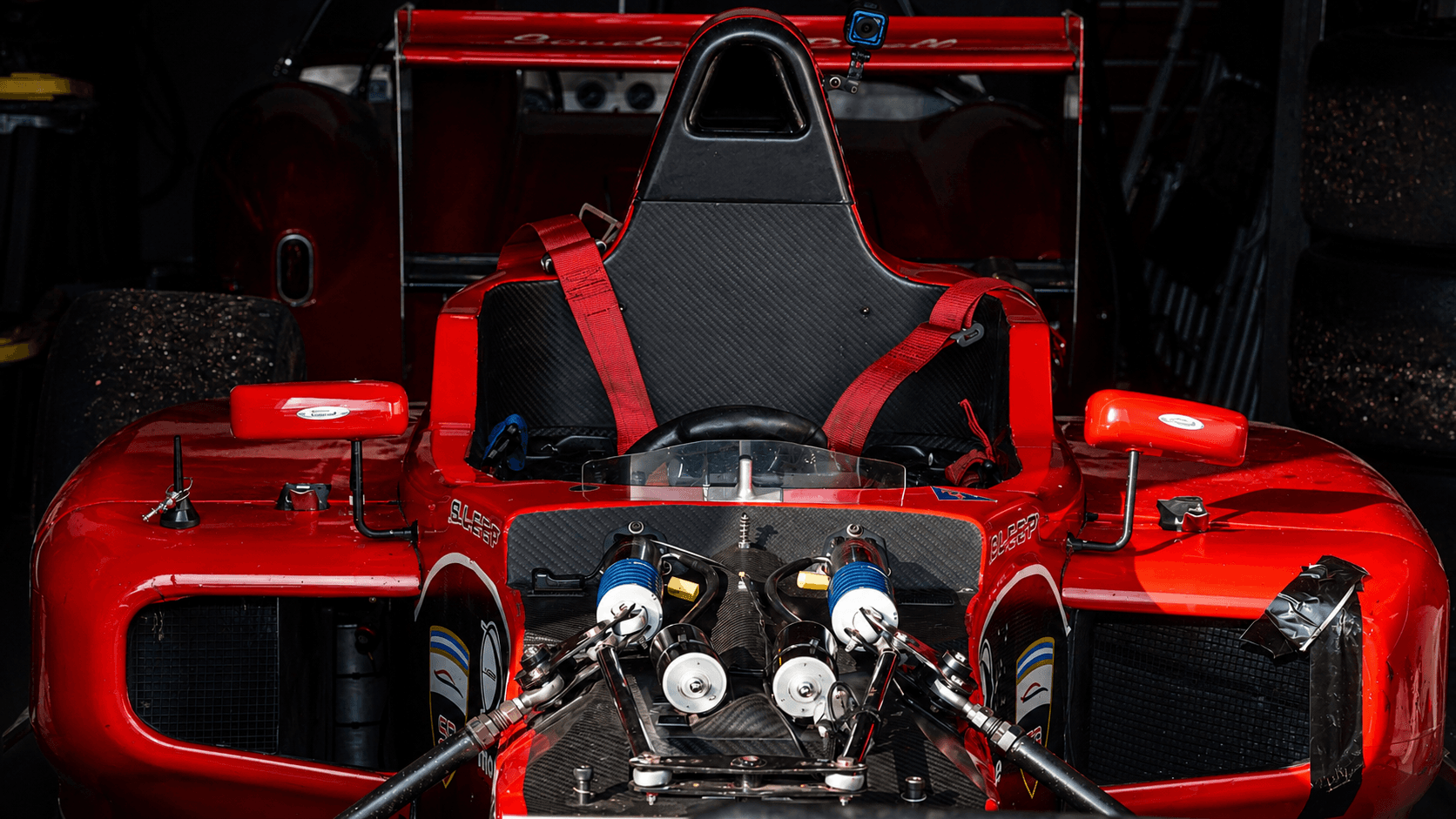 Red formula car front view in a garage preparation setting