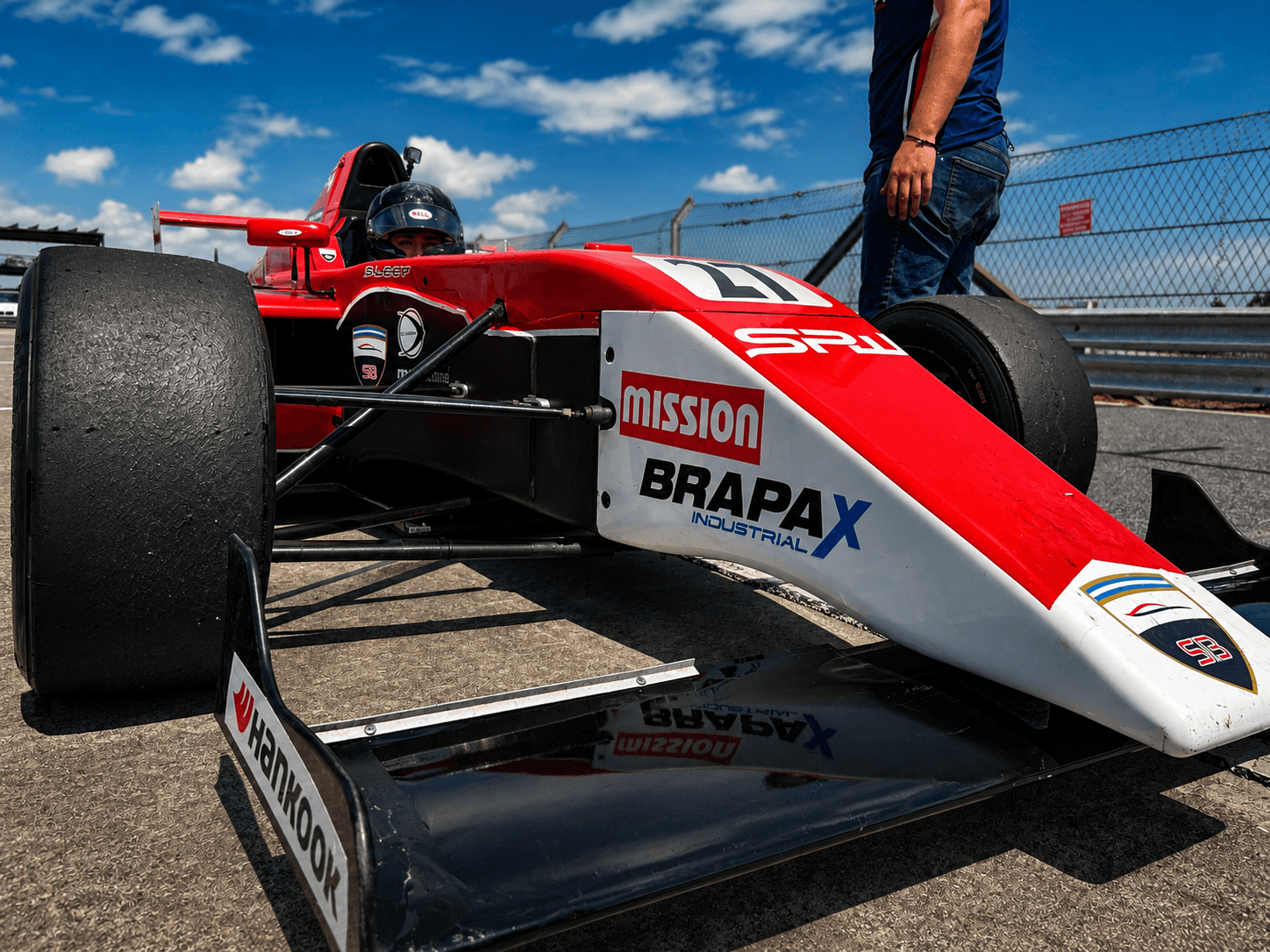 Red and white formula car in the pit lane from a low angle