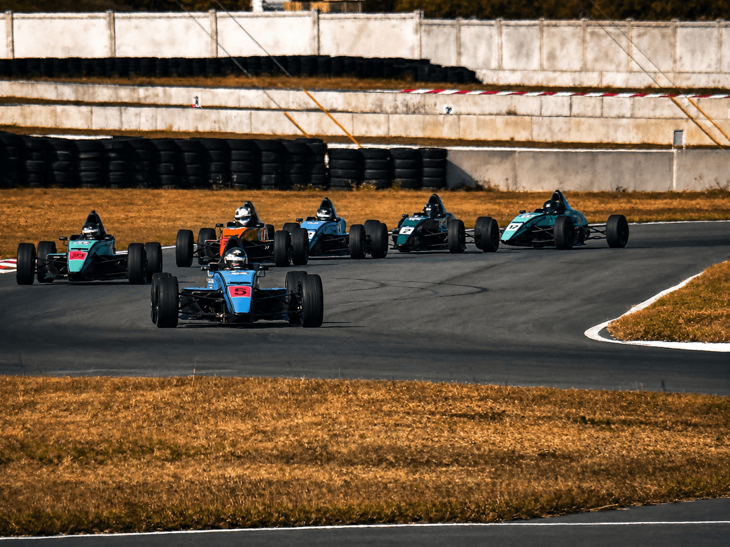 Open-wheel cars side by side during Lucas Oil race school activity